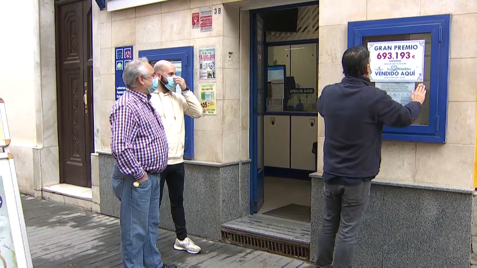 Loteros colocando en la administración el cartel del premio
