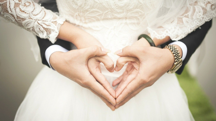 Dos novios realizan el gesto del corazón con sus manos