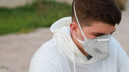 Una persona joven sola con mascarilla sentada en el suelo