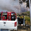 Un coche de bomberos frente a una columna de humo en el campo