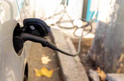 Un coche enchufado en un punto de carga - Imagen de archivo.