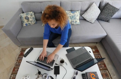 El teletrabajo no podrá suponer una merma de las condiciones laborales respecto a los empleados presenciales. Una mujer trabaja con dos ordenadores portátiles desde el salón de su casa.