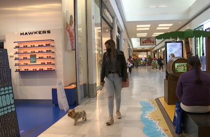 Una clienta paseando con su perra en el Centro Comercial El Faro en Badajoz.