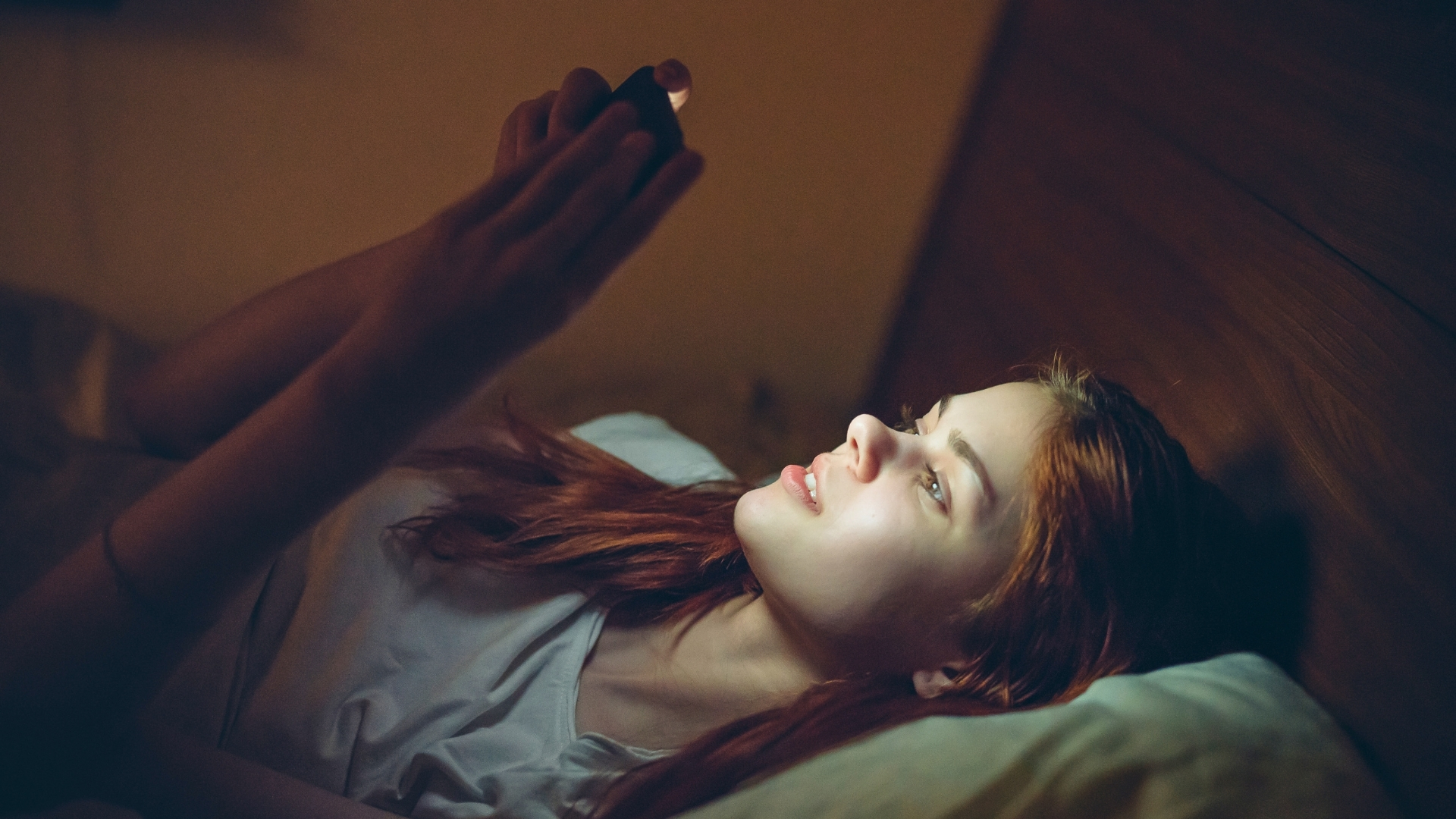 Una joven mira el móvil en la cama antes de dormir