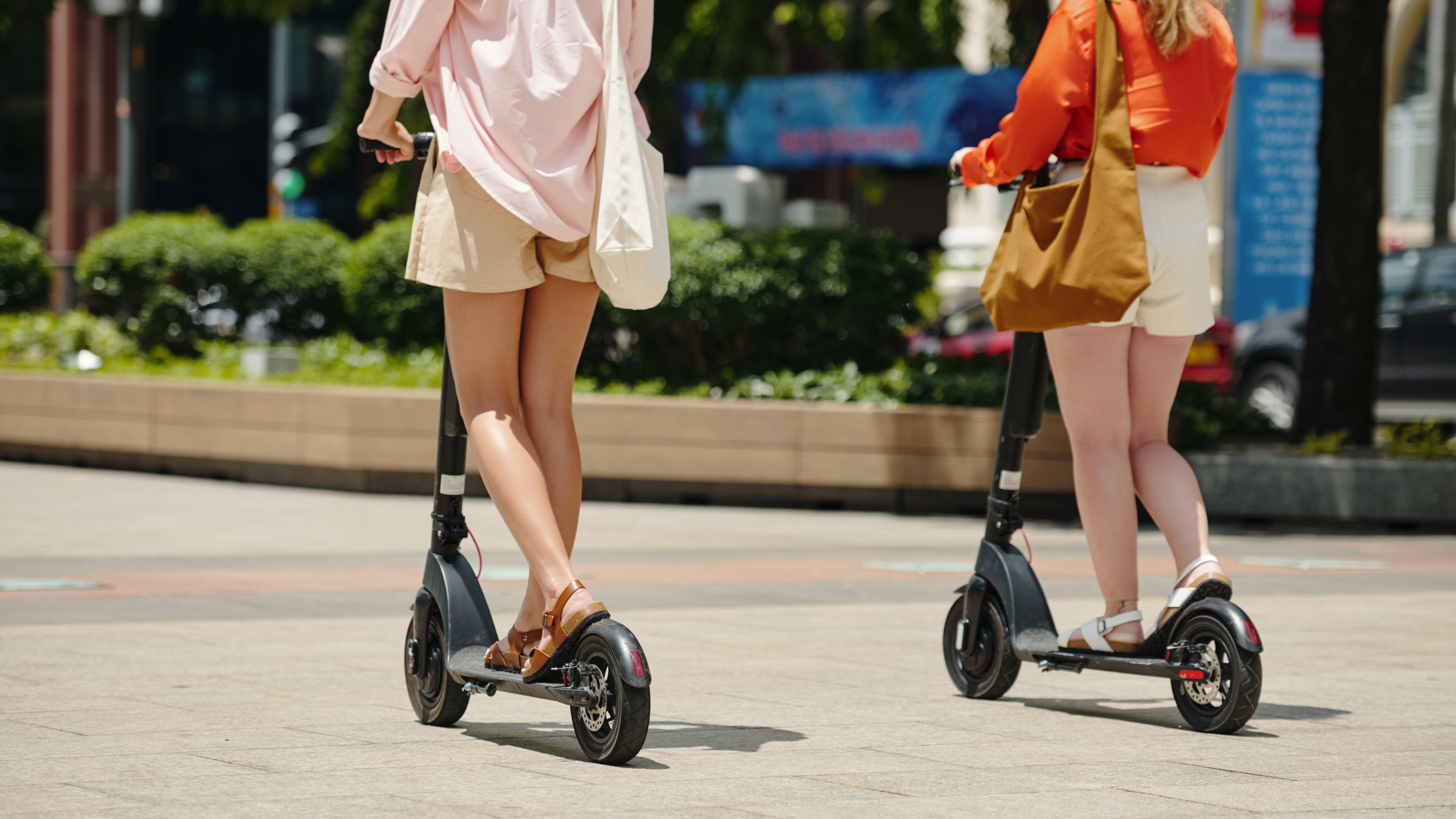 Dos personas circulando con patinete eléctrico por una ciudad. 