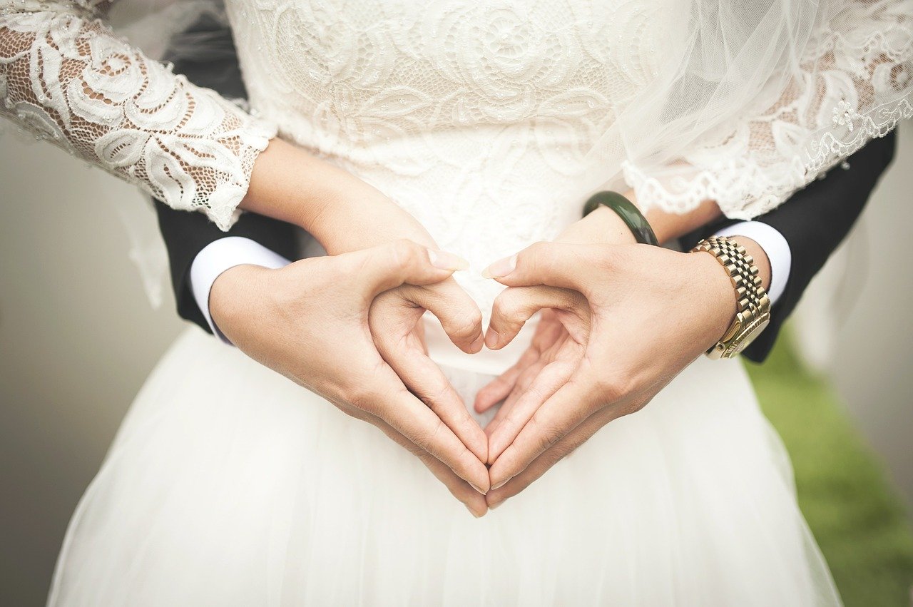 Dos novios realizan el gesto del corazón con sus manos