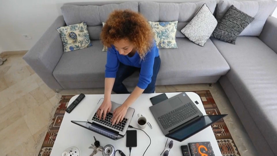 El teletrabajo no podrá suponer una merma de las condiciones laborales respecto a los empleados presenciales. Una mujer trabaja con dos ordenadores portátiles desde el salón de su casa.