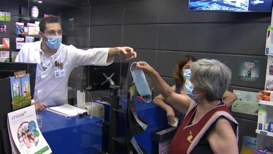 Empleado dando una mascarilla en una farmacia de Elvas