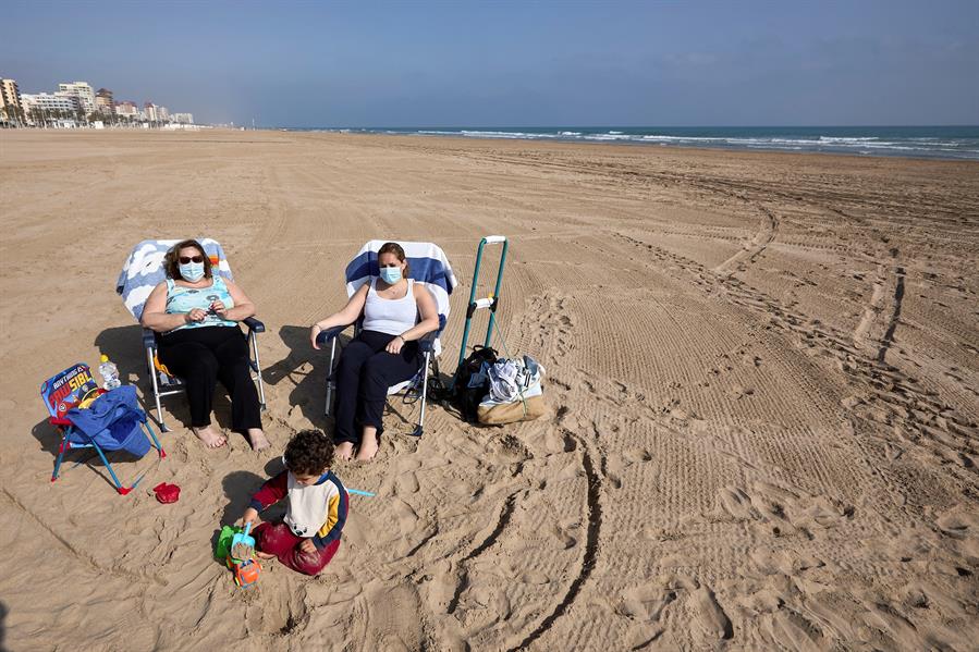 Turistas con mascarillas en la playa de Gandía
