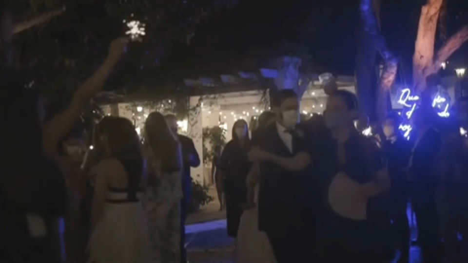 Novios e invitados bailan por la noche en unos jardines