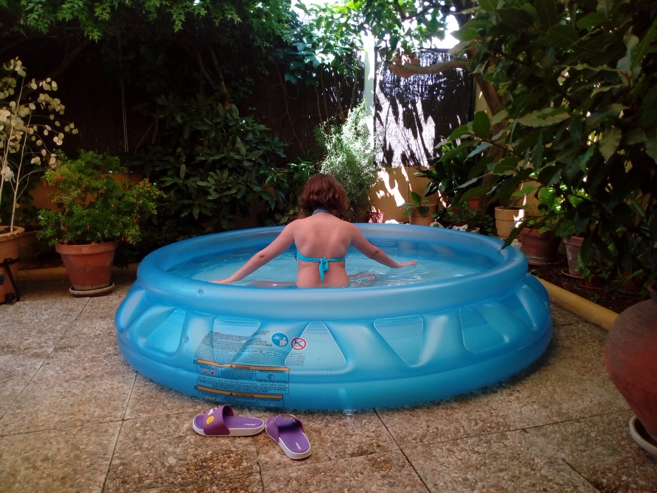 Una niña se da un baño en la piscina de su terraza.
