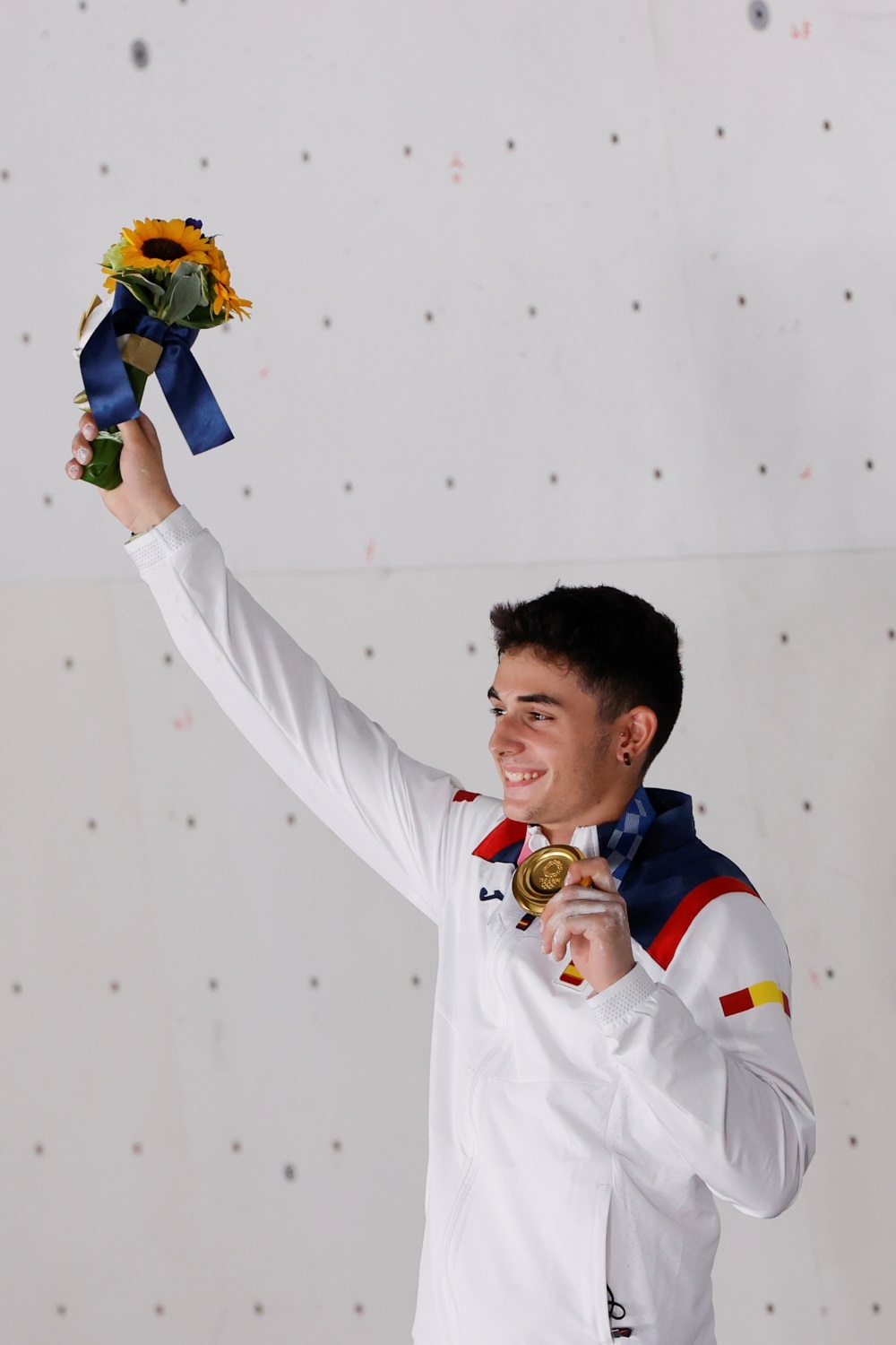El español Alberto Ginés celebra en el podio tras conseguir la medalla de oro en escalada