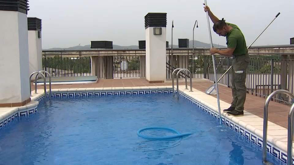 Un trabajador se encarga de la limpieza y mantenimiento de una piscina comunitaria