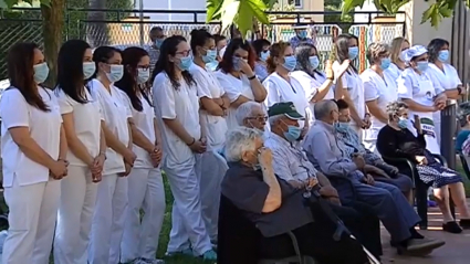 personal sanitarios y mayores en el exterior de la residencia durante un acto de homenaje