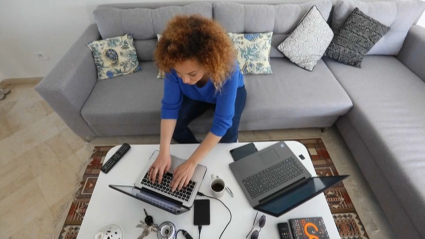 El teletrabajo no podrá suponer una merma de las condiciones laborales respecto a los empleados presenciales. Una mujer trabaja con dos ordenadores portátiles desde el salón de su casa.