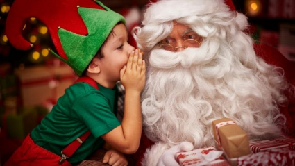 niño disfrazado de elfo hablando con Papá Noel