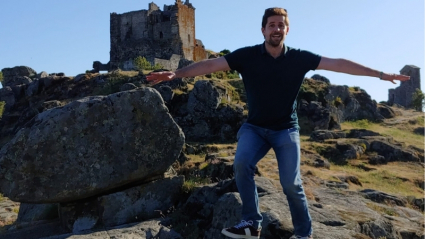 Carlos Gata con los brazos abiertos delante de un castillo