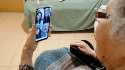 Una anciana recibiendo una videollamada de sus familiares desde una residencia de mayores