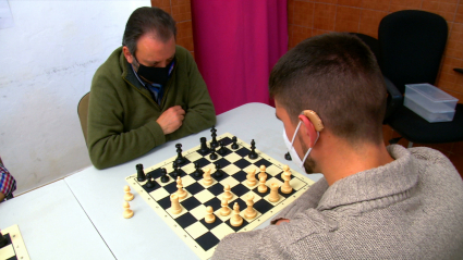 Personas sordas jugando al ajedrez. Audífono. Discapacidad auditiva