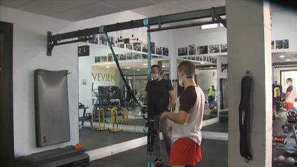 Imagen de dos personas entrenando en un gimnasio durante la pandemia