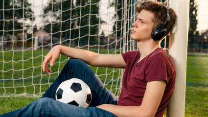 Chico escuchando música con un balón de fútbol