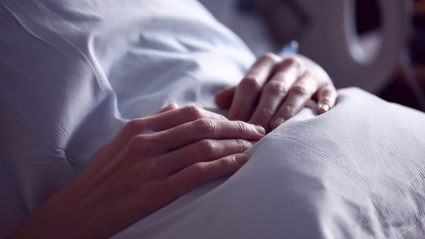 Manos de un paciente en una cama de hospital
