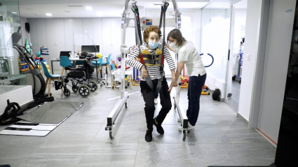 Una paciente usando, con la ayuda de su fisioterapeuta, la máquina antigravitatoria