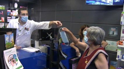 Empleado dando una mascarilla en una farmacia de Elvas