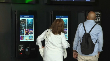 Una pareja de jubilados mira la cartelera de un cine en Badajoz