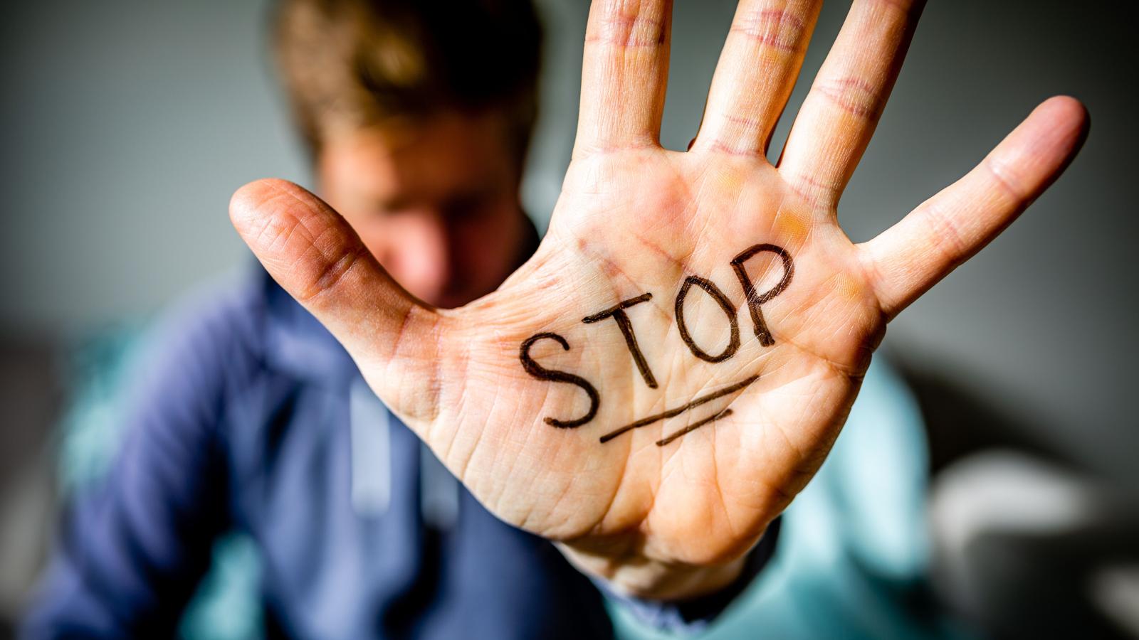 Un chico muestra la palabra STOP en la palma de la mano. 