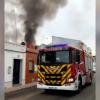 Vivienda incendiada en Montijo junto a un camión de los bomberos que trabaja en su extinción