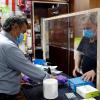 El trabajador de una ferretería atiende a un cliente con guantes, mascarilla y una pantalla protectora