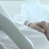 Manos de una anciana en su cama de hospital.