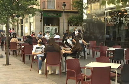 Clientes consumiendo en la terraza de un bar.
