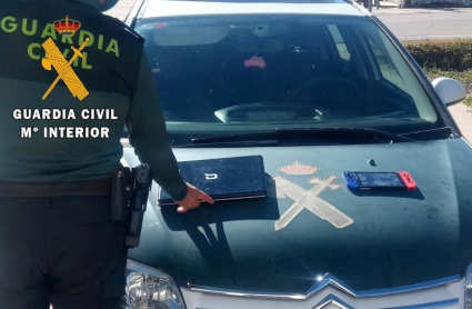 Un agente muestra algunos de los objetos recuperados en la casa y que supuestamente habían sido robados