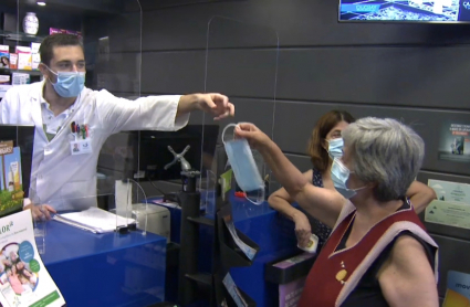 Empleado dando una mascarilla en una farmacia de Elvas
